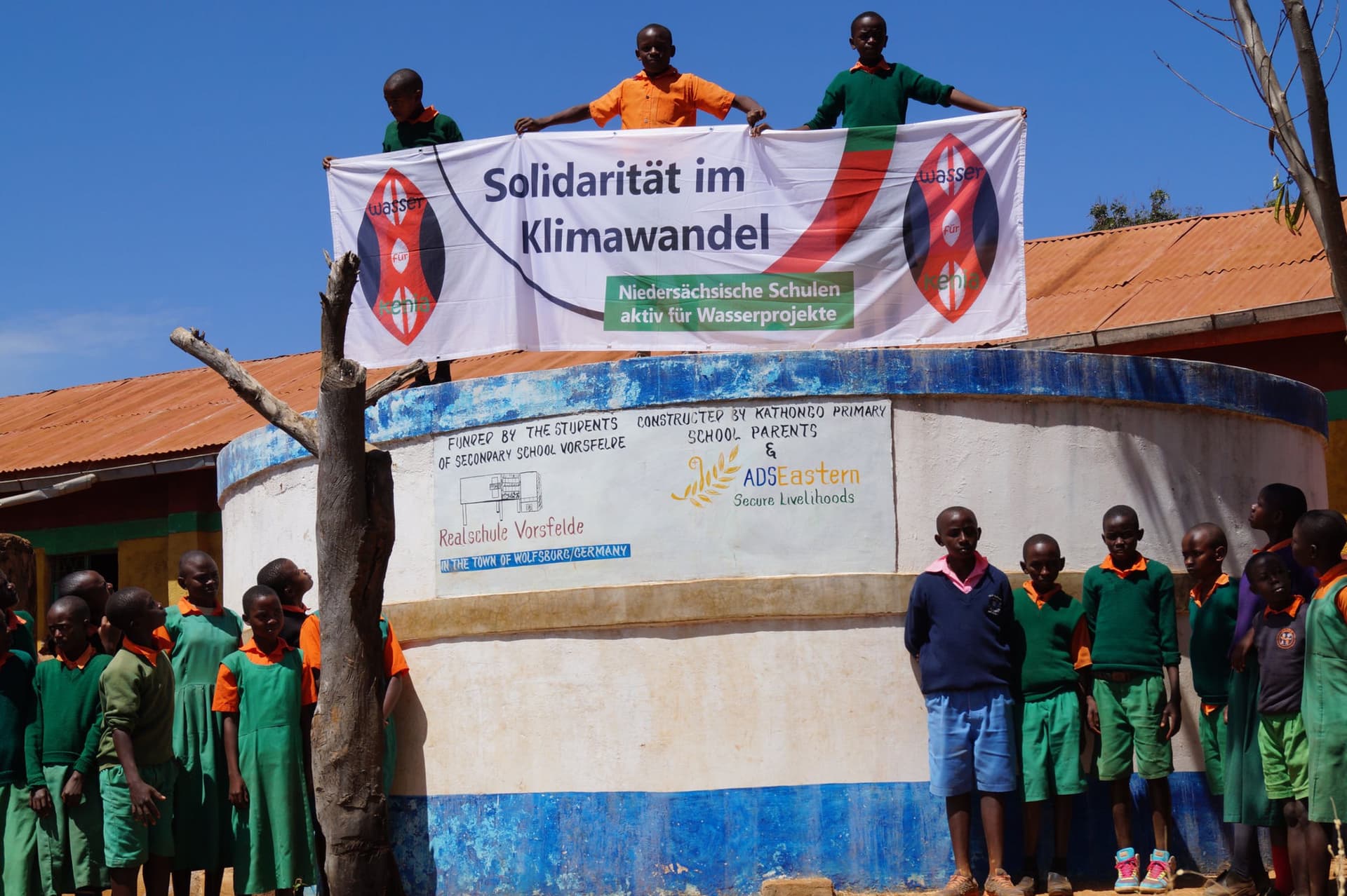 Schulkinder mit Solidaritätsbanner auf dem Wassertank der Kathongo Primary School